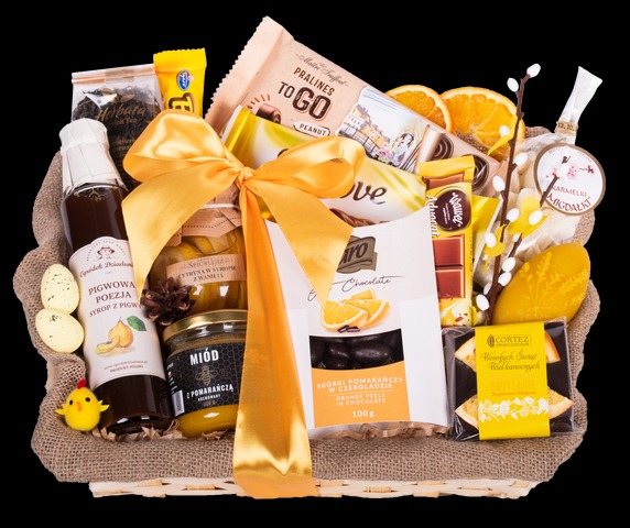 Bogato wypełniony kosz z produktami spożywczymi, takimi jak miód z pomarańczą, syrop pigwowy, praliny, czekolada z pomarańczą, cytryny w syropie, dekorowany żółtą wstążką i drobnymi dekoracjami...