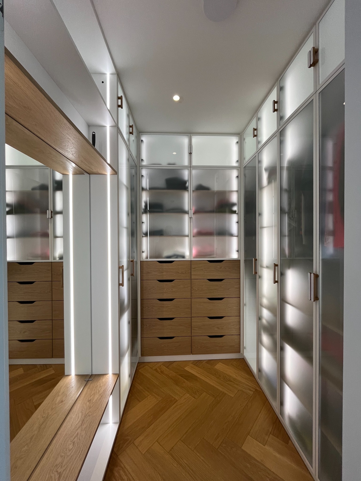 Nowoczesna szafa wnękowa z oświetleniem LED i drewnianymi szufladami, widok z perspektywy wnętrza garderoby, Legnica.