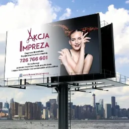 Billboard reklamujący fryzjera damsko-męskiego z hasłem 'Akcja Impreza' na tle panoramy miasta.