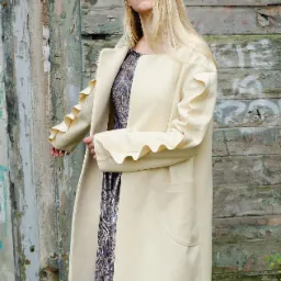 Wełniany płaszcz z falbanami na rękawach.