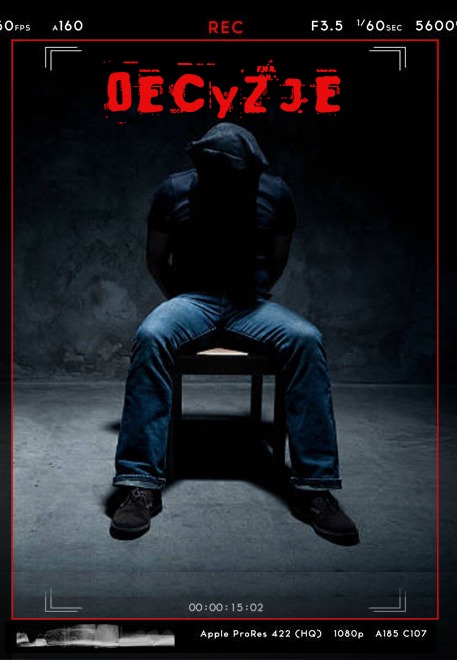 Mężczyzna w kapturze, siedzący na krześle w ciemnym pomieszczeniu, z napisem 'DECYZJE' wyświetlanym nad nim, stylizowane na nagranie wideo.