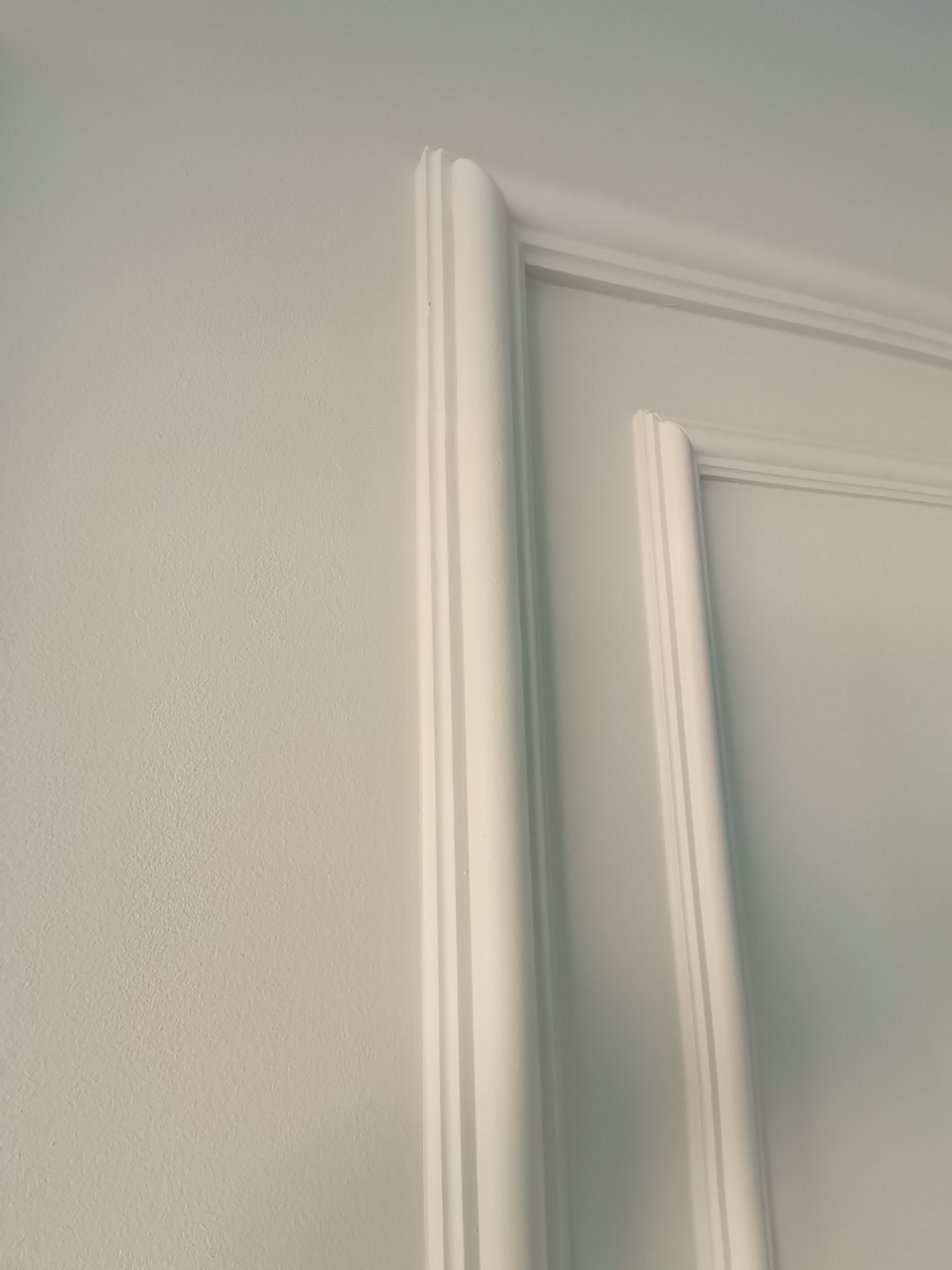 Biała ściana z ozdobną, frezowaną listwą przypodłogową i górną, tworzącą ramę.