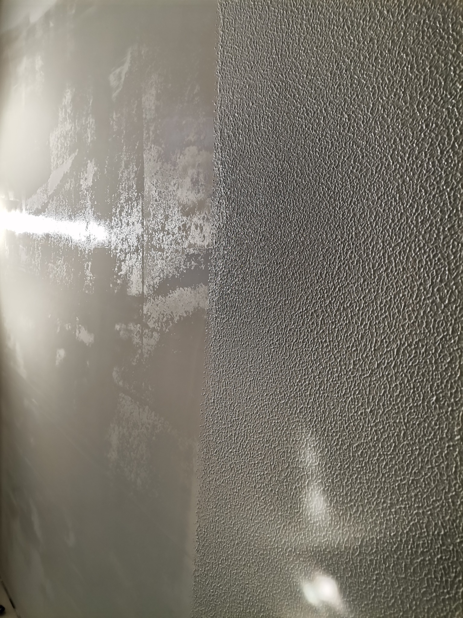 Fragment ściany, na której widoczna jest różnica między powierzchnią po nałożeniu gładzi a powierzchnią z fakturą, z wyraźnym podziałem na dwie strefy.