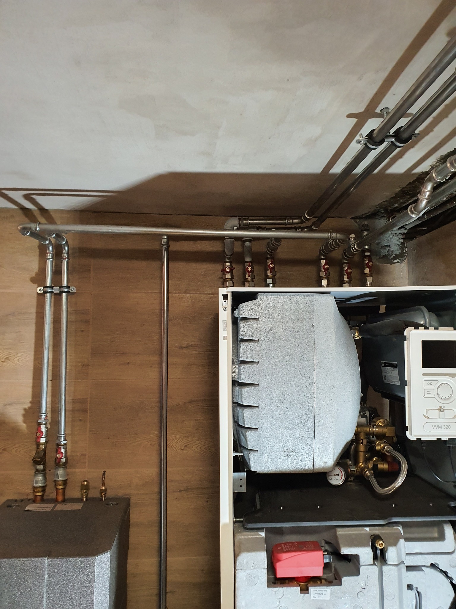 Zamontowany piec centralnego ogrzewania z widocznymi rurami instalacji grzewczej w Krakowie, z bliska, z widocznym panelem sterowania VVM 320.