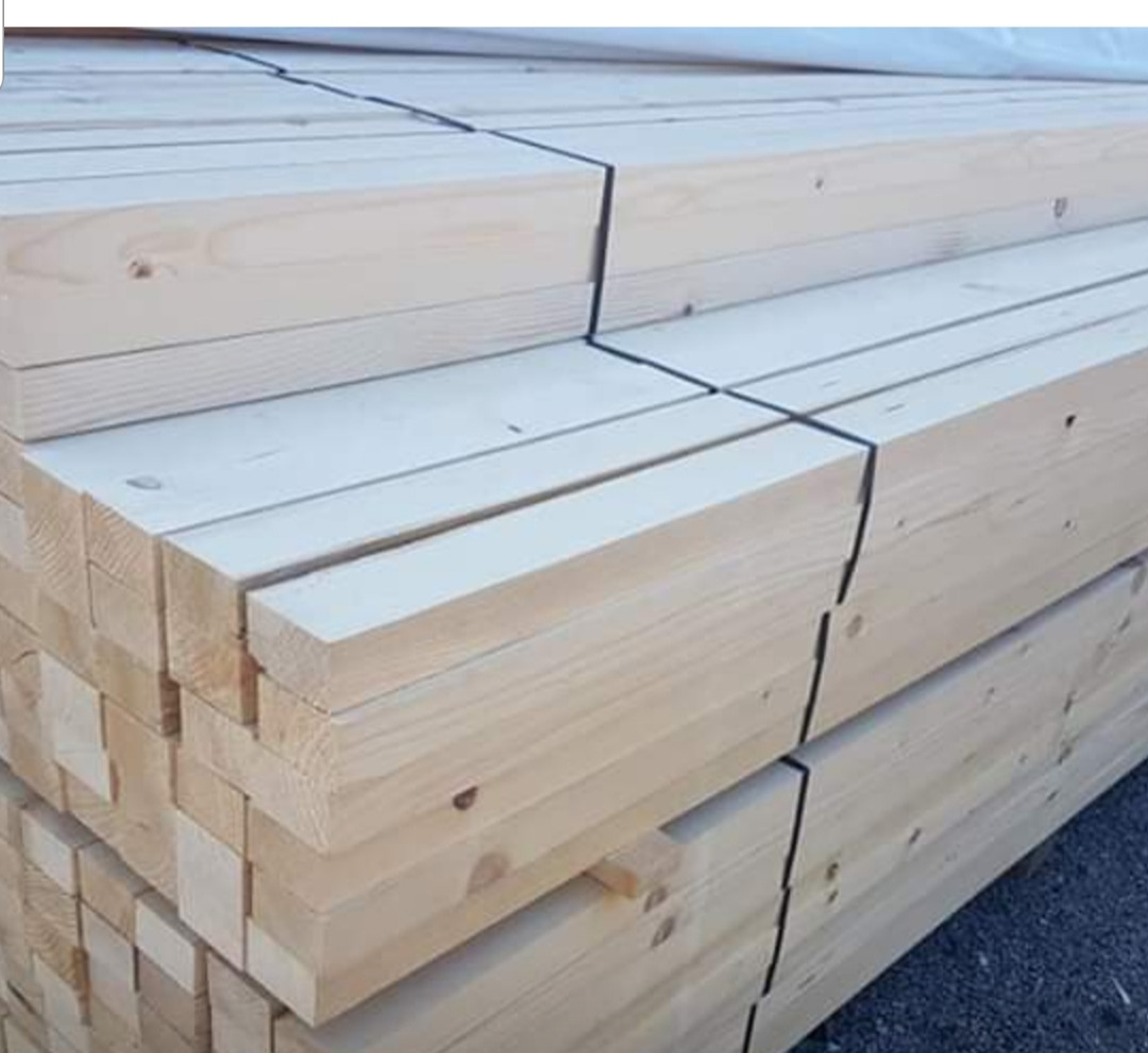 Stos belek z jasnego drewna, spiętych czarną taśmą, widoczne sęki i naturalny rysunek drewna.