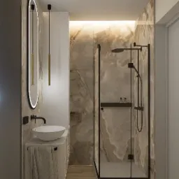 Nowoczesna łazienka z kabiną prysznicową typu walk-in z czarnymi ramami, umywalką nablatową na szafce z ręcznikiem, podświetlanym lustrem owalnym i marmurowymi płytkami na ścianach