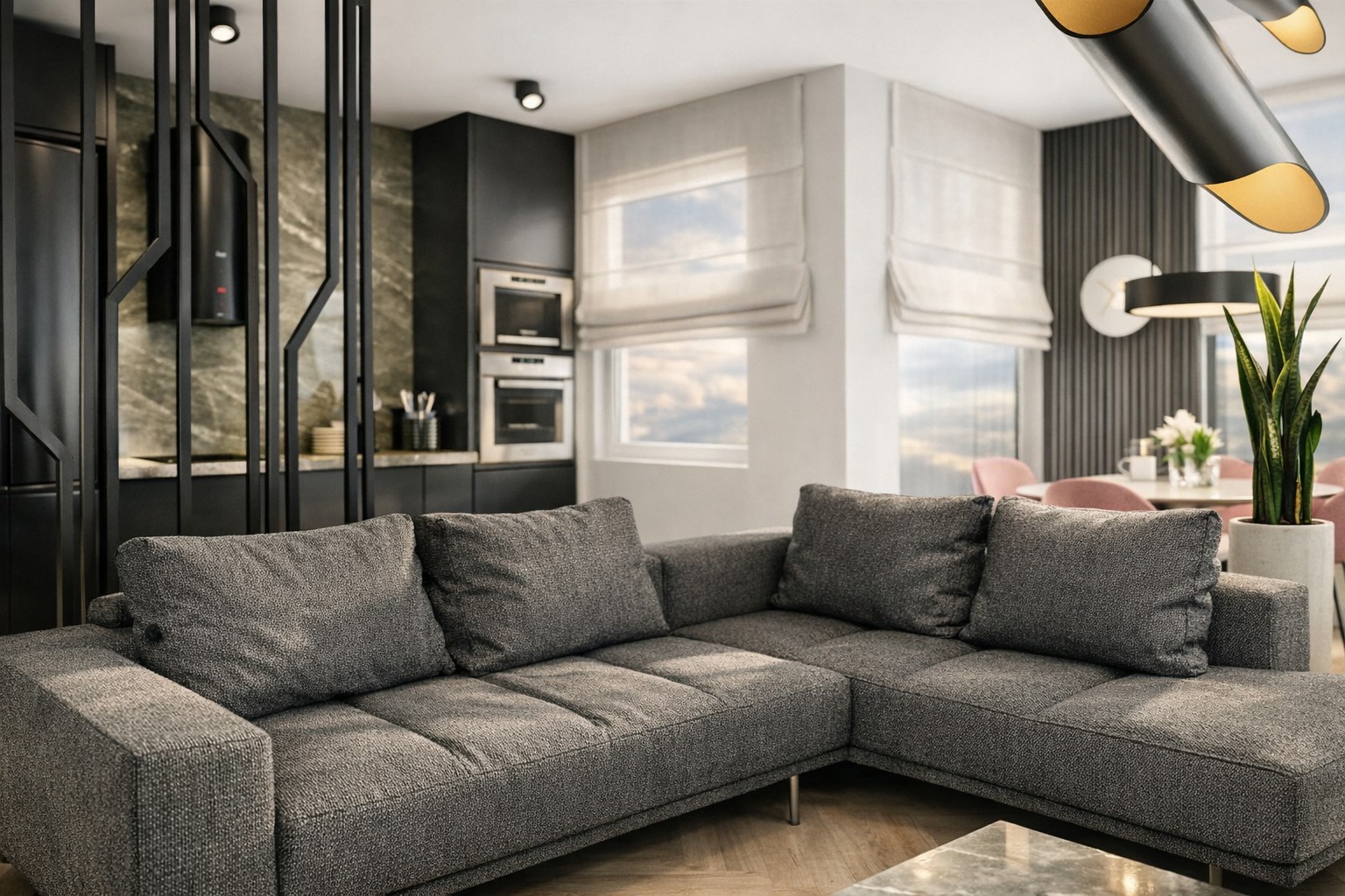 Nowoczesny salon z szarą sofą narożną i czarną kuchnią w tle, oświetlony designerską lampą. Aranżacja wnętrz w Starachowicach.