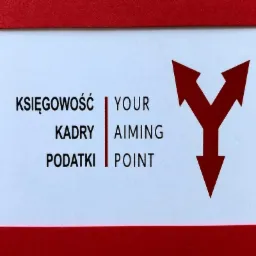 Grafika firmowa w kolorach czerwieni i bieli, z napisem 'KSIĘGOWOŚĆ KADRY PODATKI' oraz 'YOUR AIMING POINT' oddzielonymi pionową linią, obok czerwona strzałka rozwidlająca się ku górze.
