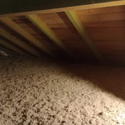 Poddasze z drewnianą konstrukcją i wypełnieniem izolacyjnym z wełny mineralnej, widoczne elementy folii paroizolacyjnej.