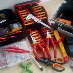 Zestaw narzędzi elektrycznych, w tym multimetr cęgowy Fluke, szczypce, wkrętaki z izolacją, ściągacz izolacji, obcinak do kabli Beta, tulejki kablowe, rękawice robocze i skrzynki narzędziowe Haupa...