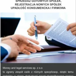 Dwie osoby omawiają dokumenty, jedna wręcza długopis drugiej, na biurku leżą dokumenty i długopisy, w tle widoczny laptop.