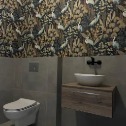 Nowoczesna łazienka z wiszącą toaletą, umywalką nablatową na szafce z drewnopodobnym dekorem i tapetą w motywy roślinne i ptasie.