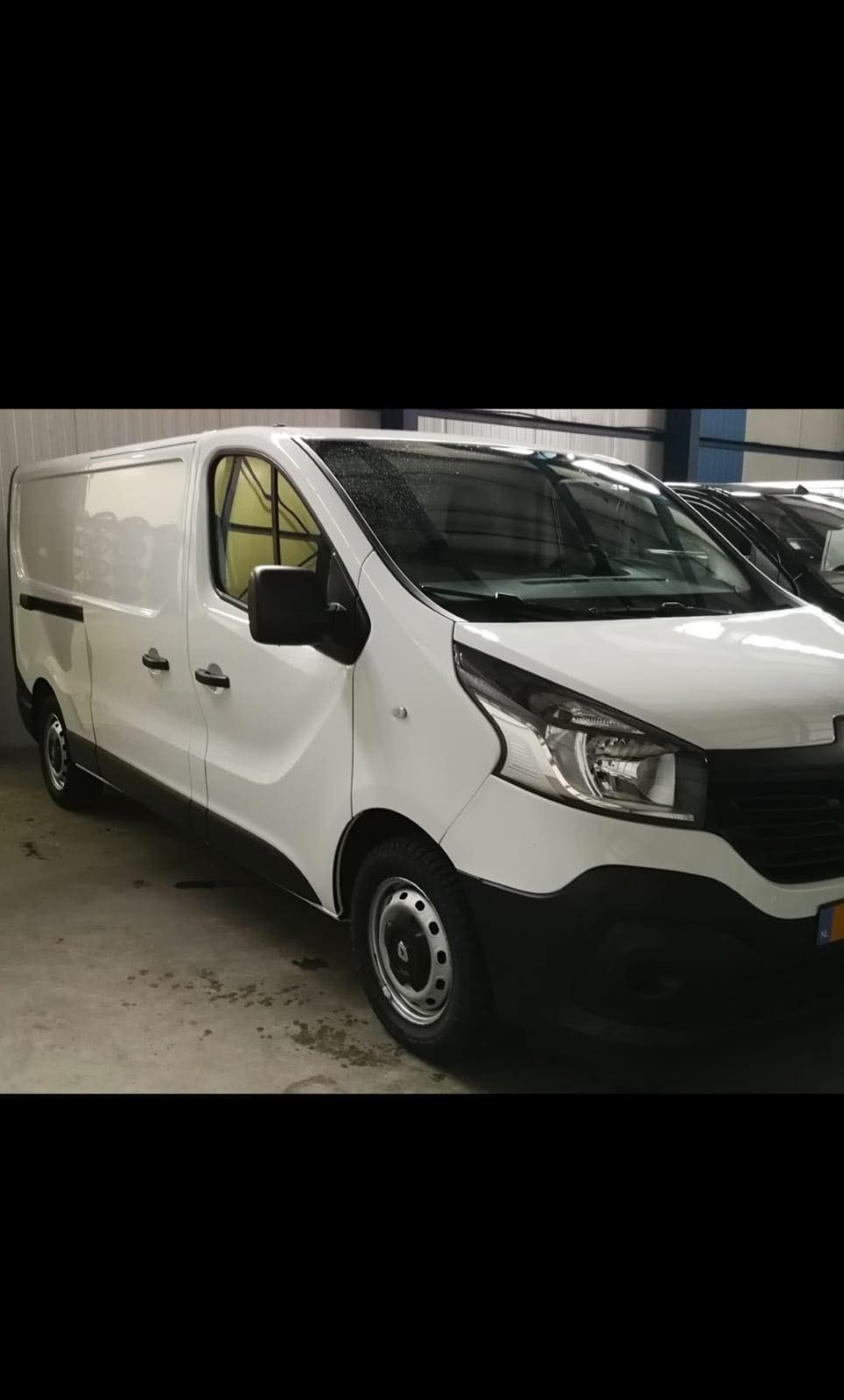 Biały samochód dostawczy Renault Trafic na parkingu, widoczne detale karoserii i opon zimowych.