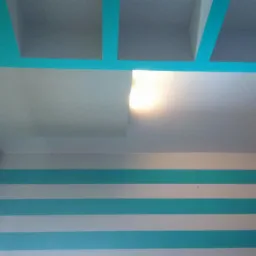 Wnętrze pokoju z dekoracyjnym sufitem podwieszanym z turkusowymi elementami, ścianą w poziome turkusowo-białe pasy i okładziną drewnopodobną na ścianie po prawej stronie.