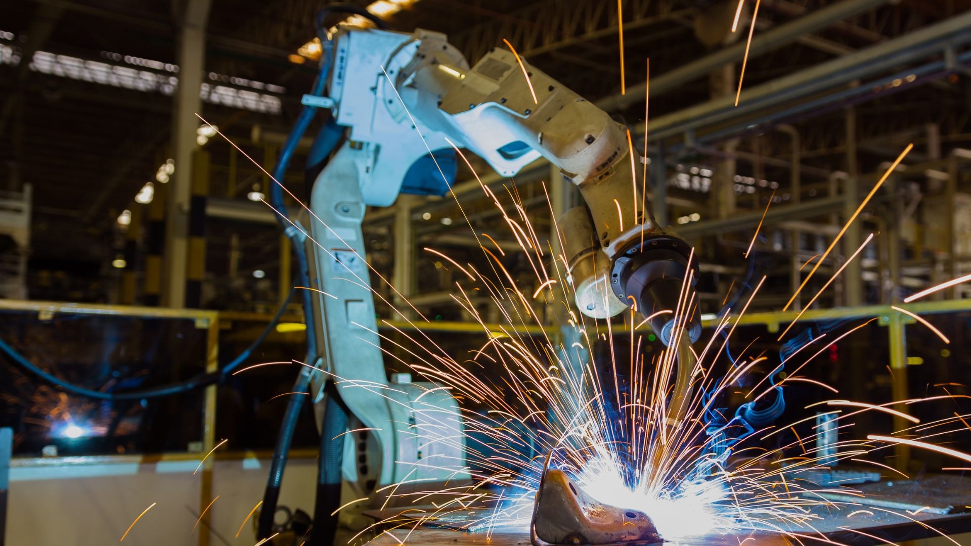 Zautomatyzowany proces spawania elementu metalowego w zakładzie w Stalowej Woli, iskry i dym w powietrzu.