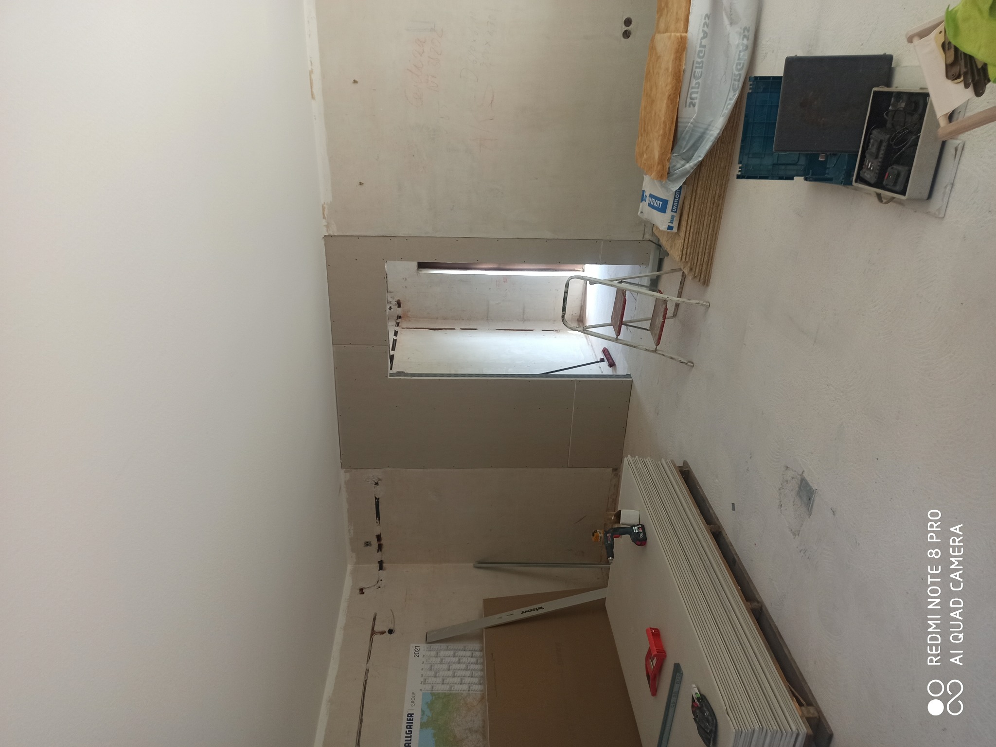 Wnętrze w trakcie remontu: widoczne płyty gipsowo-kartonowe, drabina, materiały izolacyjne i narzędzia, ściany przygotowane do dalszych prac wykończeniowych.