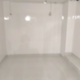 Yuriy Romanenko usługi budowlane - Pusty, jasny pokój po remoncie, świeżo pomalowane ściany i podłoga, widoczne przewody elektryczne pod sufitem.