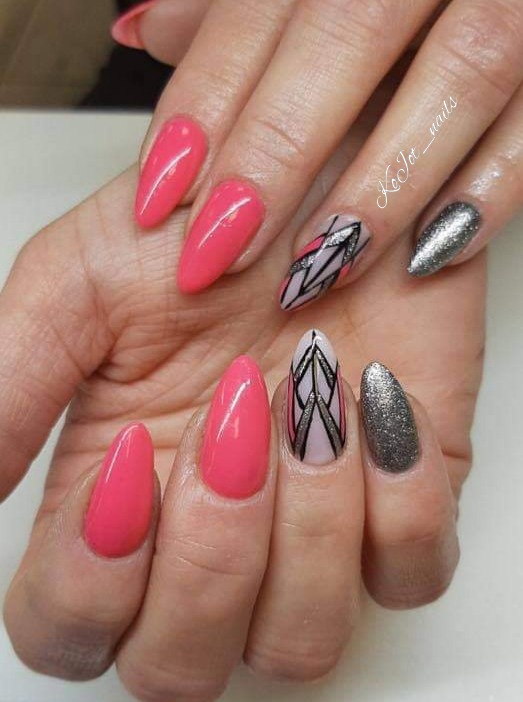 Dłoń z migdałowymi paznokciami: trzy pomalowane na intensywny róż, jeden srebrny brokat i dwa z geometrycznym wzorem w czerni, bieli i różu.
