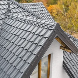 Szary dach modułowy Budmat Venezia X-Matt 455 na domu jednorodzinnym, widok z góry, jesienne drzewa w tle.