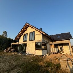 Kierownik Budowy/Inspektor Nadzoru Krystian Lindstaedt - Budowa domu jednorodzinnego w stanie surowym otwartym, widoczne bloczki, okna, dach pokryty dachówką, teren wokół posesji w trakcie przygotowania.