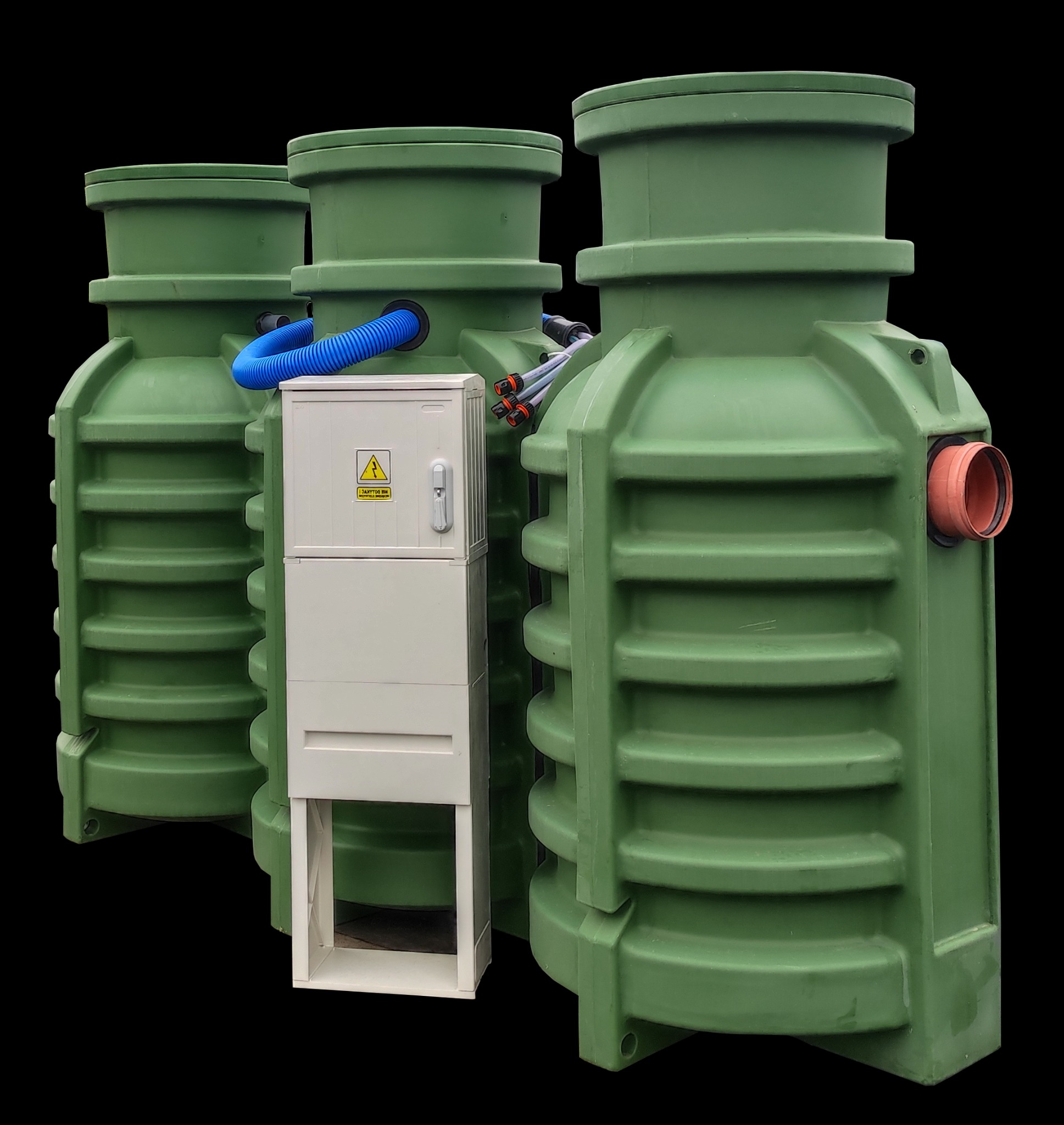 Trzy zielone, plastikowe zbiorniki z instalacją elektryczną i rurami przyłączeniowymi na czarnym tle. Widoczna tabliczka ostrzegawcza na skrzynce elektrycznej.