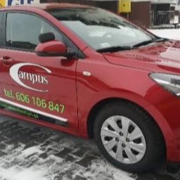 Campus Wszechnica Edukacyjna Małgorzata Dąbrowska - Czerwony samochód z logo i numerem telefonu na drzwiach, zaparkowany na śniegu.