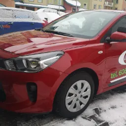 Czerwony samoch&oacute;d z logo 'Campus' i numerem telefonu na boku, stojący na śniegu.