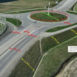 Skan 3D ronda z naniesionymi pomiarami długości i kątów, widok z góry, teren zielony wokół ronda, chodnik, jezdnia, bariera ochronna, współrzędne geodezyjne.