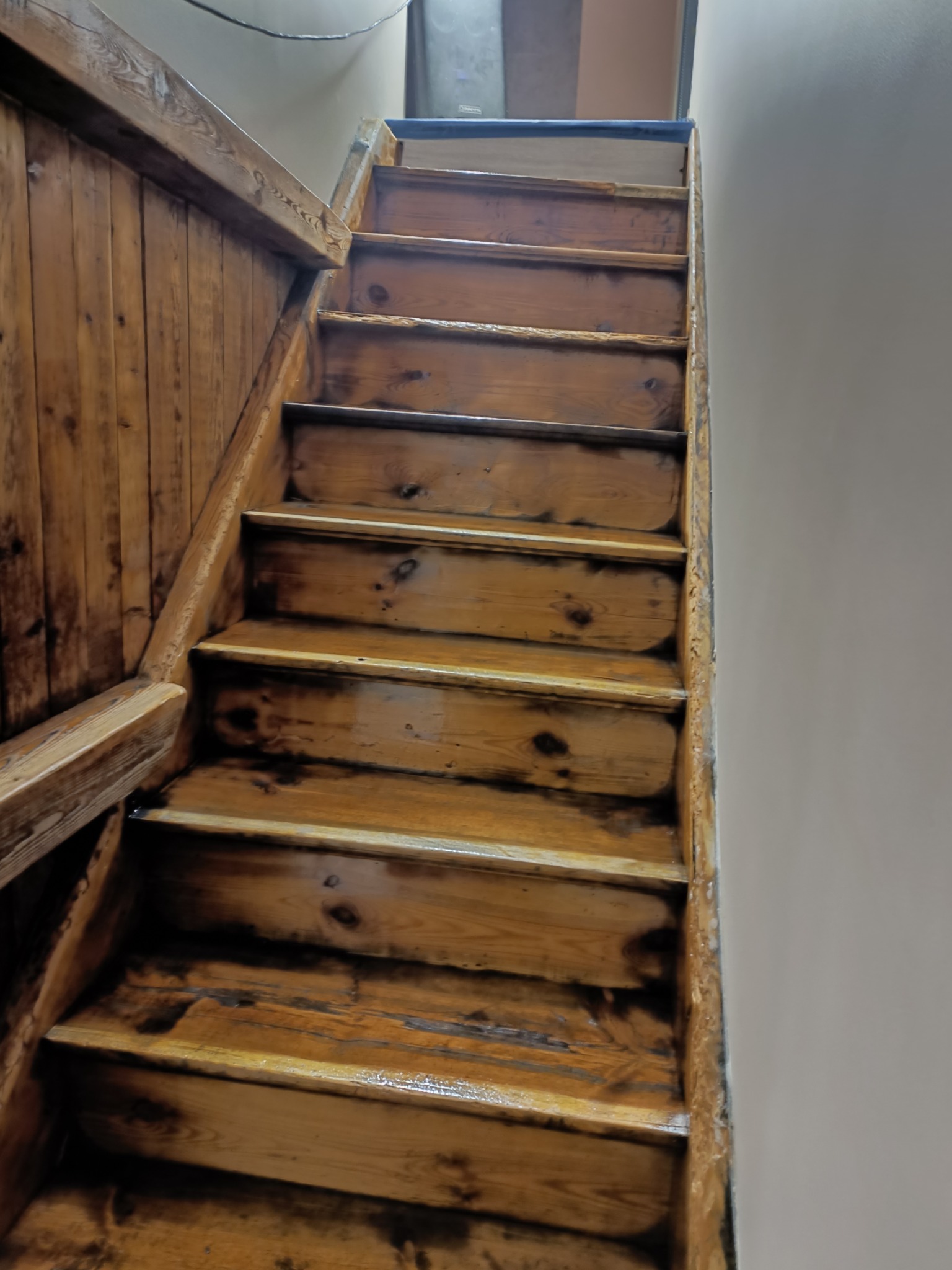 Drewniane schody po renowacji w domu w Jerzykowie, widok z dołu, ukazujący sęki i strukturę drewna po lakierowaniu.