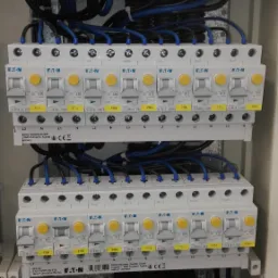 Rozdzielnica elektryczna z zamontowanymi bezpiecznikami EATON, widoczne okablowanie i oznaczenia faz