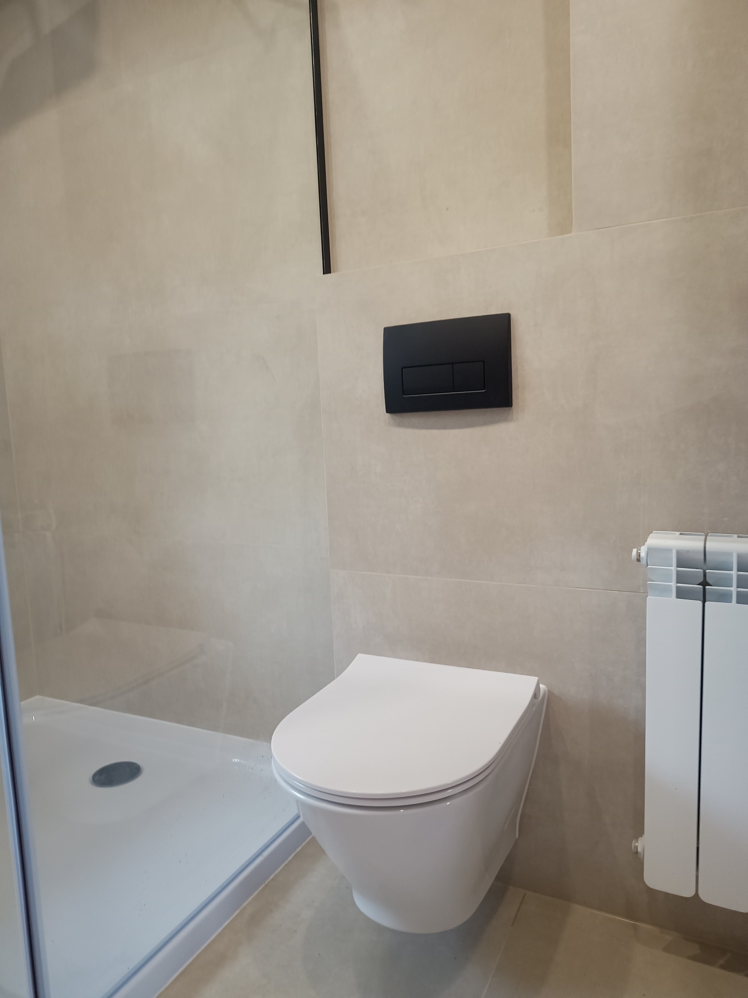 Nowoczesna toaleta podwieszana i kabina prysznicowa w jasnej łazience, wykończonej płytkami w Sieprawiu. Minimalistyczny design i funkcjonalność.