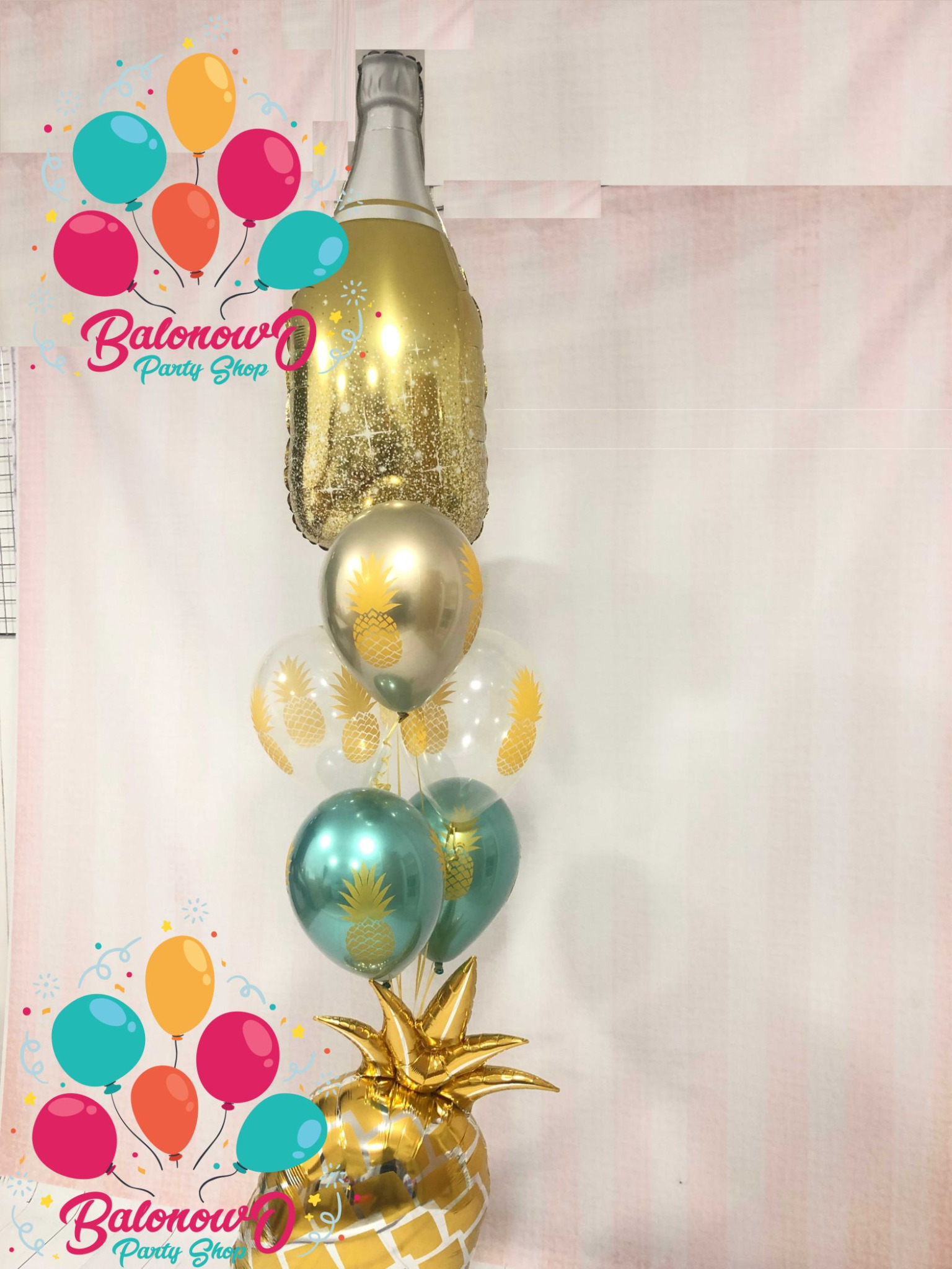 Kompozycja balonowa z motywem ananasa i butelki szampana, z logo sklepu z balonami, idealna na imprezę tematyczną.