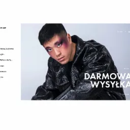 Mężczyzna z intensywnym makijażem oczu w stylizowanej kurtce ze skóry węża, prezentowany na stronie internetowej z napisem 'Darmowa Wysyłka' i odnośnikiem do sklepu.