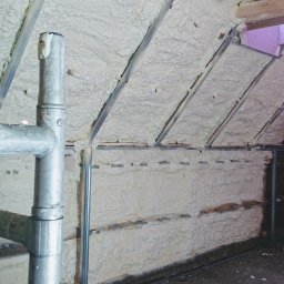 Uslugi Ogólnobudowlane Sławomir Słowik - Poddasze z ukośnymi ścianami pokryte sztywną pianą izolacyjną, widoczne metalowe profile konstrukcyjne i fragment rusztowania.