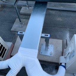 NOVA KLIMATYZACJE - Instalacja klimatyzacji na dachu: rury owinięte białą taśmą, połączone z jednostką zewnętrzną, metalowa korytka kablowa, betonowe podstawy.
