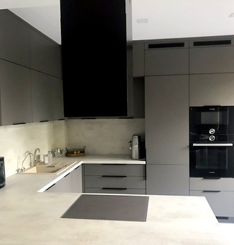 Nowoczesna kuchnia w odcieniach szarości z czarnymi akcentami w Bielsku Podlaskim, widoczny blat kuchenny, szafki wiszące i piekarnik w zabudowie.