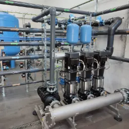 Kompleksowa instalacja przemysłowa: rurociągi z oznaczeniami kierunku przepływu, zbiorniki ciśnieniowe i pompy obiegowe w sterylnej hali.