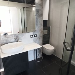 PRO-FLIZ - Nowoczesna łazienka z czarnymi płytkami podłogowymi, szarą mozaiką na ścianach, wiszącą białą miską WC, umywalką nablatową na czarnej szafce z ryflowanym frontem i szklaną kabiną prysznicową...