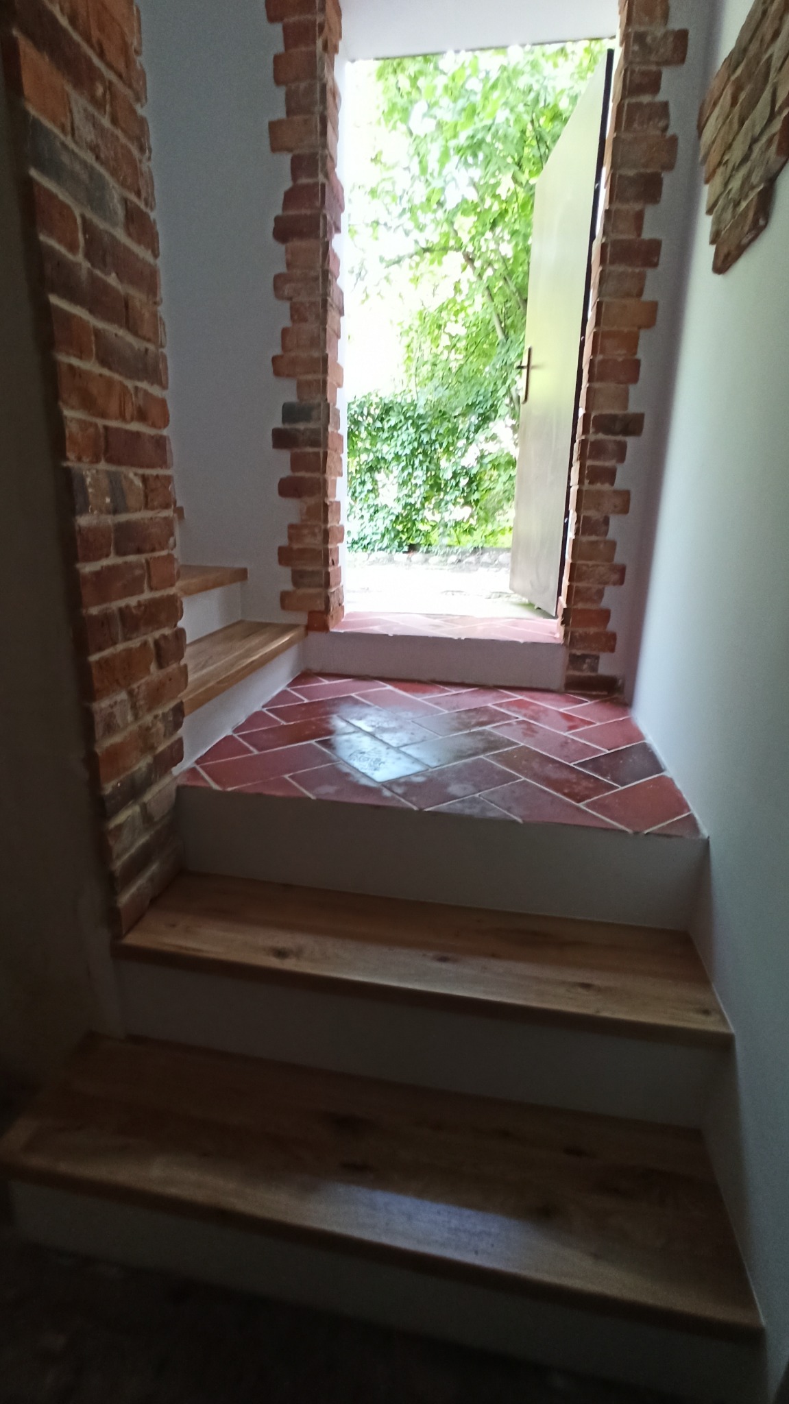 Schody z drewnianymi stopniami i wykończeniem ceglanym prowadzące na zewnątrz.