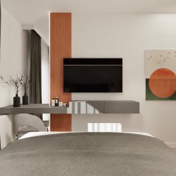 FUNKCJONALNE WNĘTRZE - studio projektowania wnętrz - Nowoczesna sypialnia z szarą tapetą, minimalistycznym biurkiem i telewizorem na ścianie. Pomarańczowy panel dekoracyjny i abstrakcyjny obraz dodają koloru.