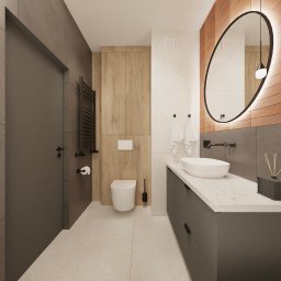 FUNKCJONALNE WNĘTRZE - studio projektowania wnętrz - Nowoczesna łazienka z drewnianymi akcentami, owalnym lustrem z podświetleniem LED i minimalistyczną umywalką nablatową. Ciemne meble i płytki tworzą elegancki kontrast.
