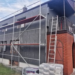 Passive Instal Sp. z o.o.- Mateusz Sztacherski - Dom w trakcie ocieplania styropianem grafitowym, widoczne rusztowanie, drabina i paczki styropianu Feidal na trawniku.