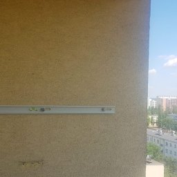Montaż klimatyzacji Stalowa Wola na balkonie w bloku - wieżowcu. Na zdjęciu widać jeden z elementów uchwytu do powieszenia klimatyzatora oraz otwór o średnicy 6 cm na przeprowadzenie dwóch miedzianych rurek w otulinie i kabla sterowniczego.