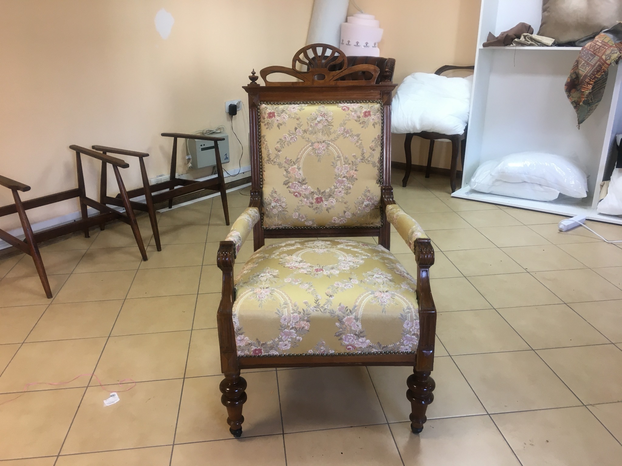 Odrestaurowany fotel w stylu vintage z drewnianą ramą i tapicerką w kwiatowy wzór, widoczne detale zdobnicze i kształtne nogi.