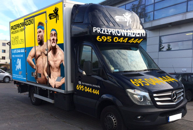 Czarny samochód dostawczy z reklamą firmy przeprowadzkowej, na której widnieją dwaj półnagie mężczyźni z numerem telefonu i hasłem 'Z nami będzie lżej'.