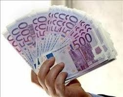 Dłoń trzymająca wachlarz banknotów 500 euro, lekko rozmazane tło.