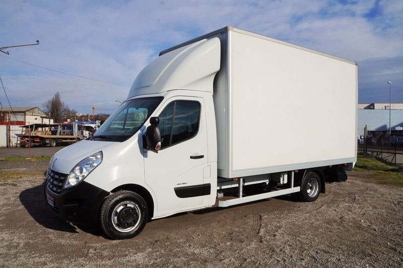 Biały Renault Master z zabudową kontenerową, zaparkowany na żwirowym placu, widoczny z boku, z lekkim pochyleniem w lewo.