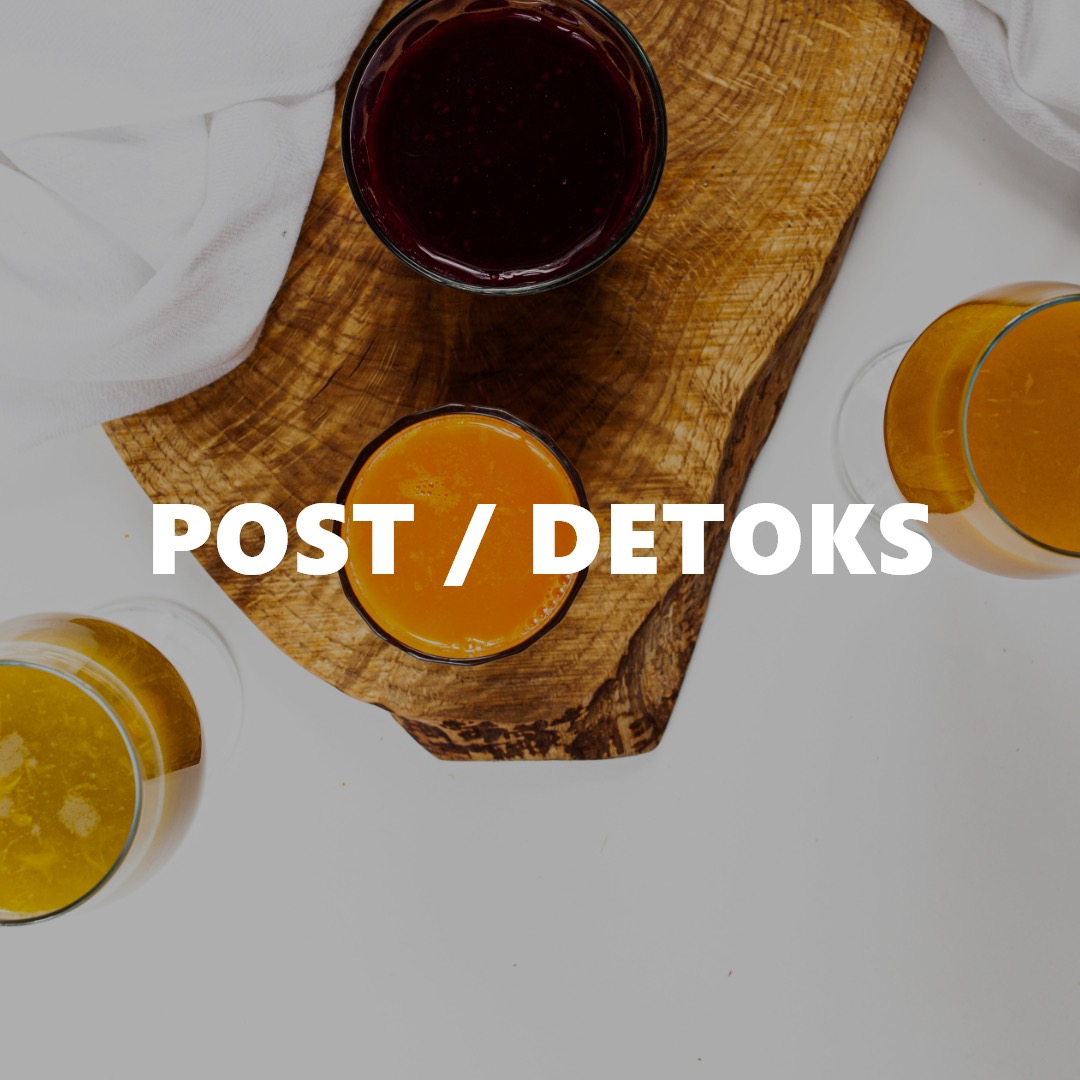 Widok z góry na trzy szklanki z kolorowymi napojami na drewnianej desce, obok biała ściereczka; napis 'POST / DETOKS' na pierwszym planie.