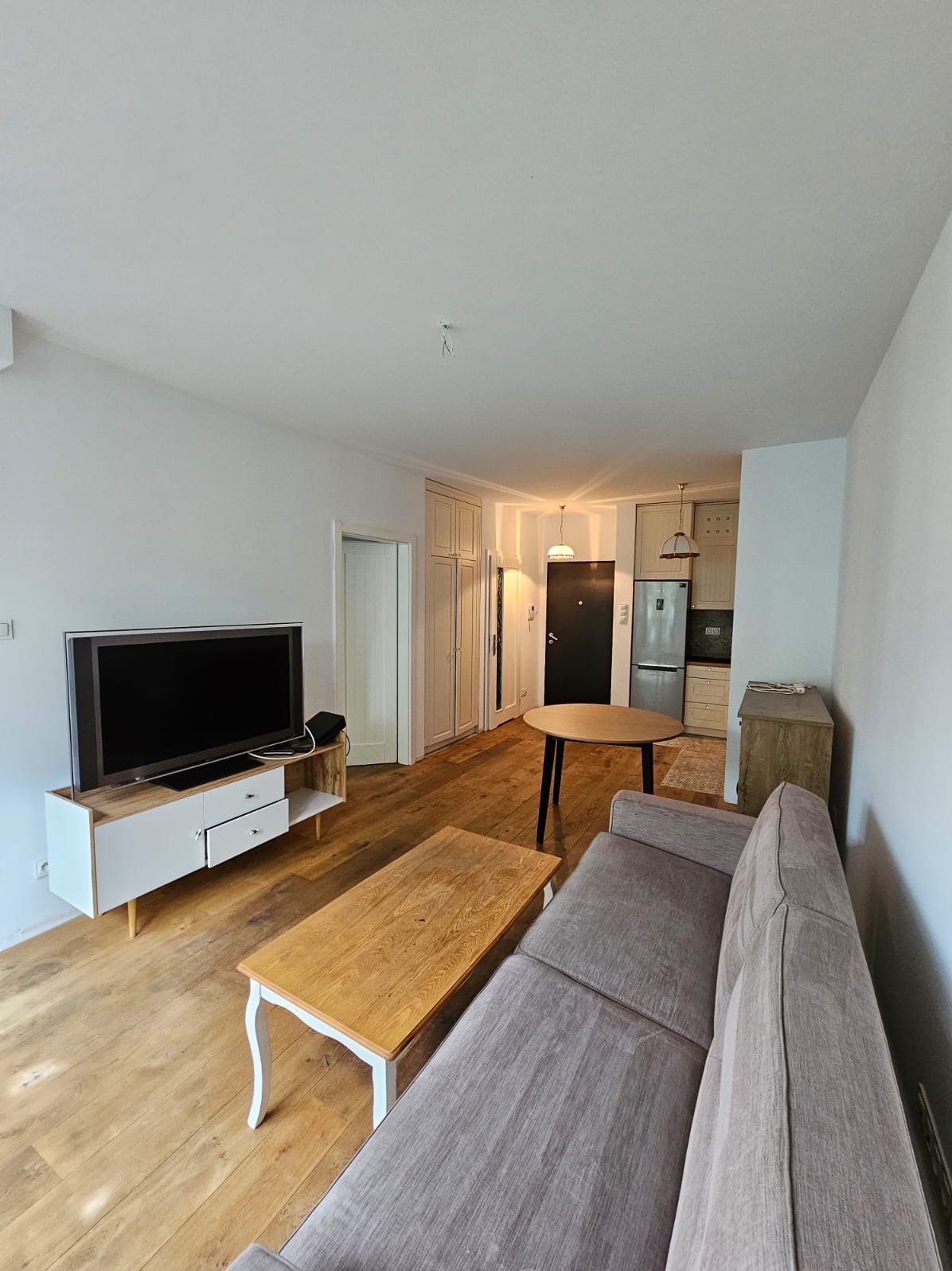 Jasne mieszkanie po remoncie: parkiet z naturalnego drewna, białe ściany, nowoczesne meble i otwarta przestrzeń kuchni.