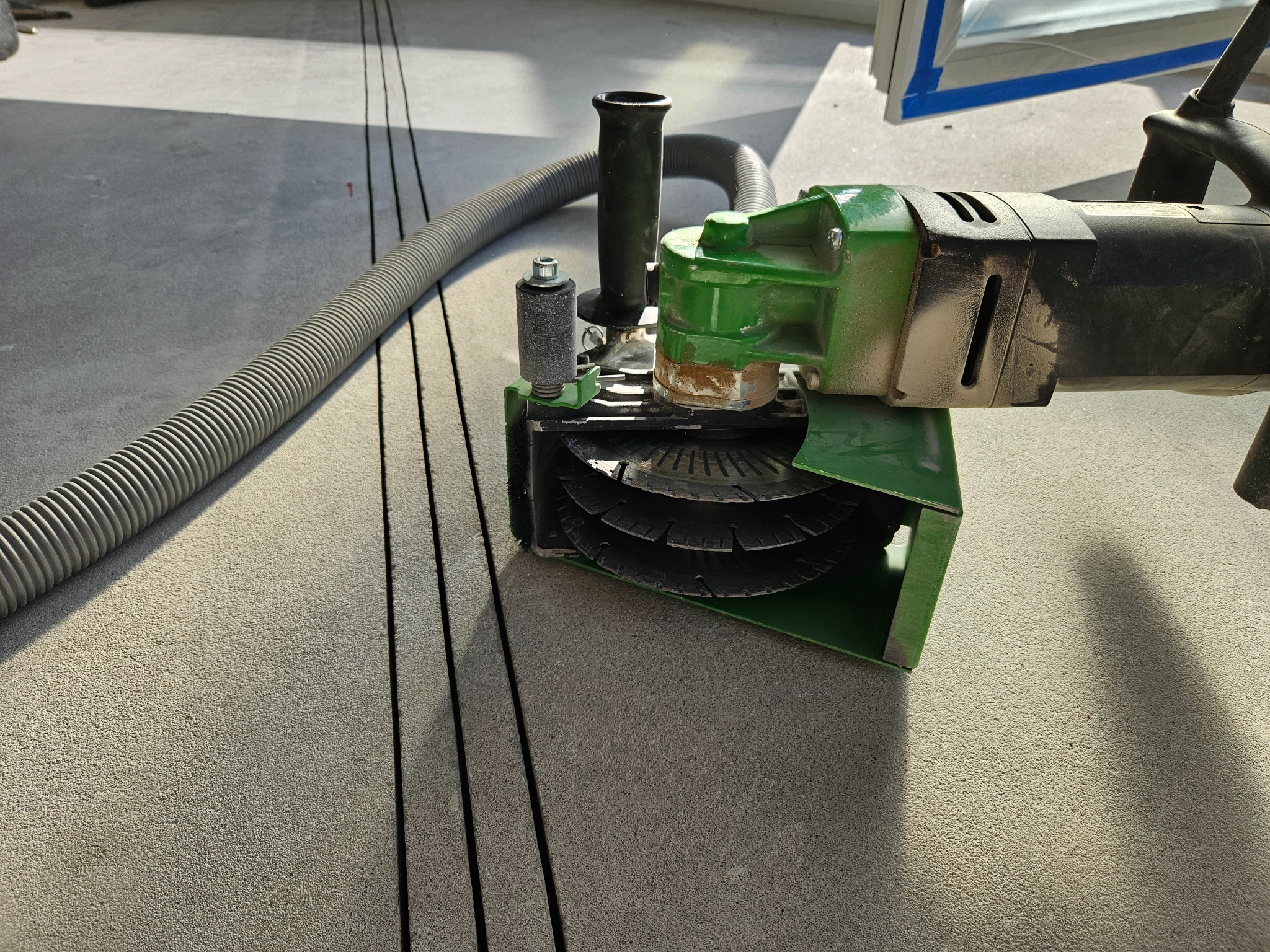 Frezarka do bruzd w posadzce z podłączonym odkurzaczem przemysłowym podczas wykonywania wycięć pod instalację klimatyzacji.